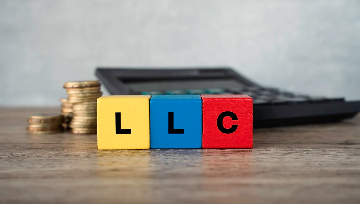 LLC block letters next to tax forms and a calculator for business tax election
